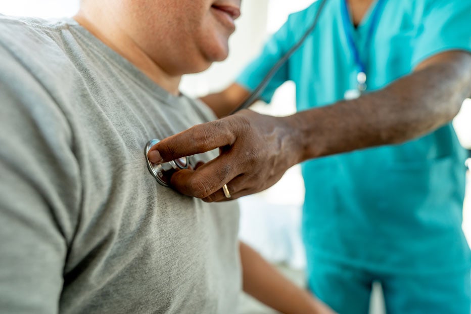 doctor uses stethescope on male patient, close up