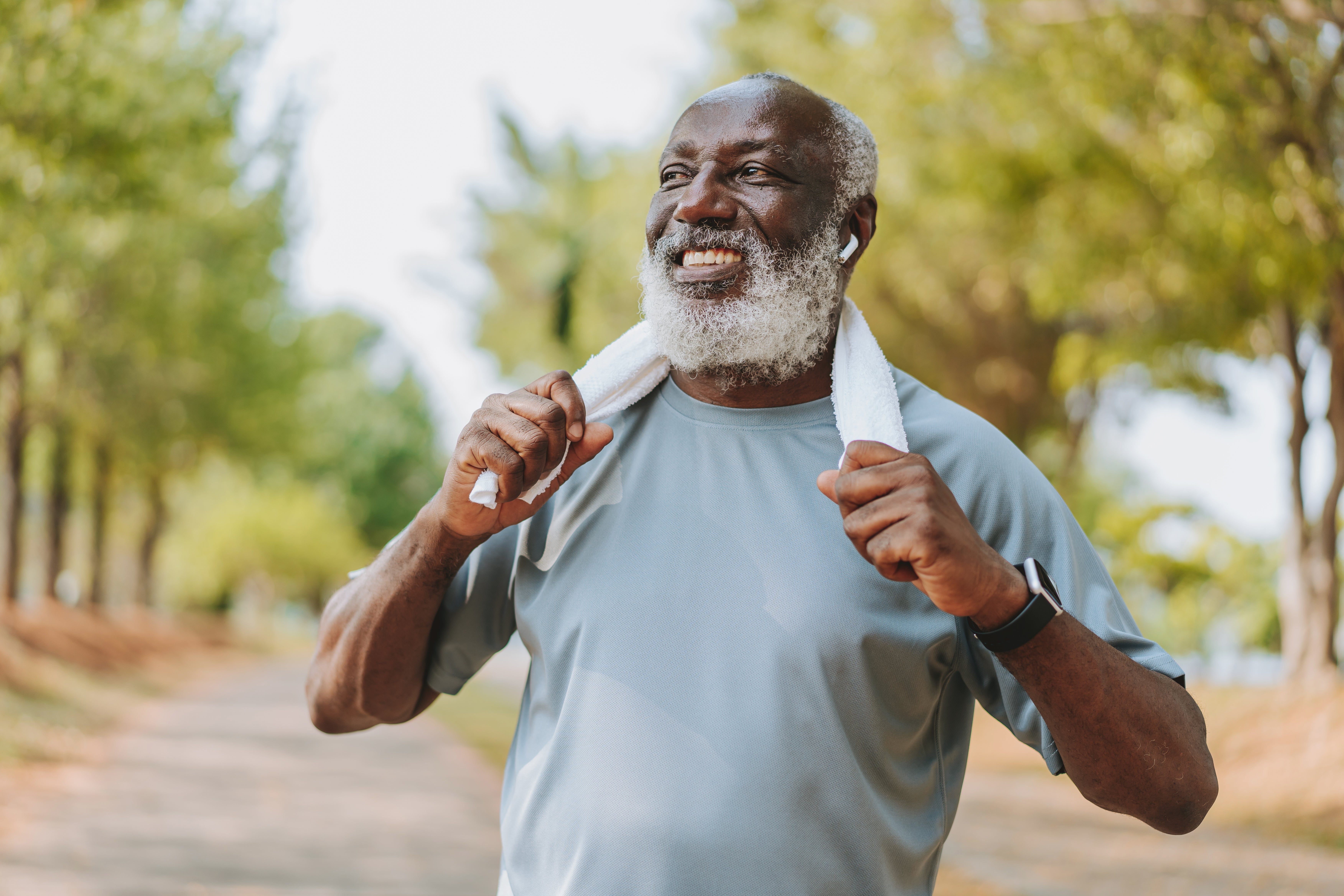An older man smiles while exercising outdoors